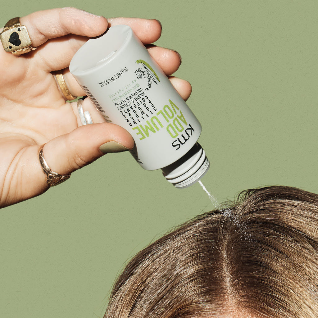 Hand applying a product to hair with a green background