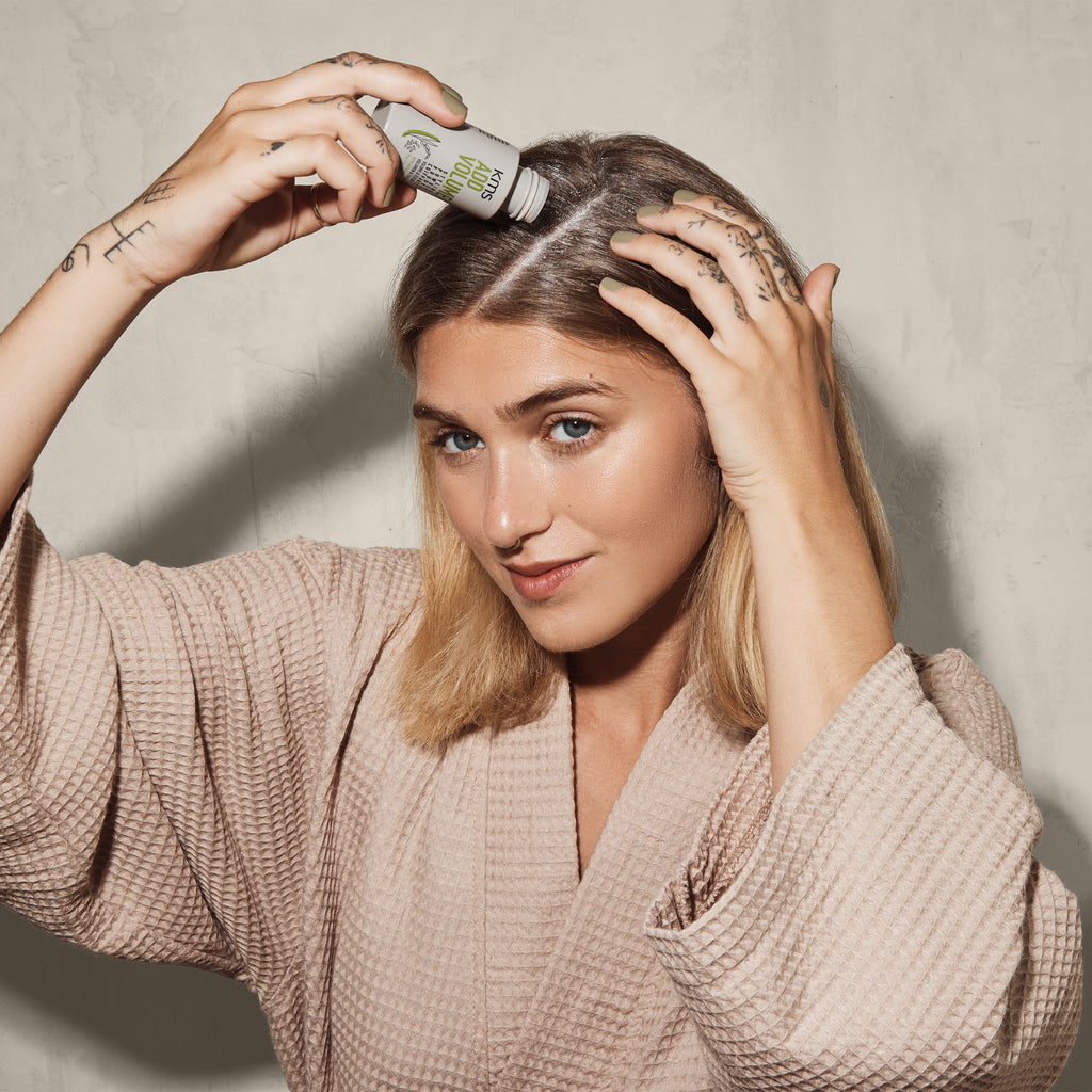Woman applying hair product to her hair in a casual setting