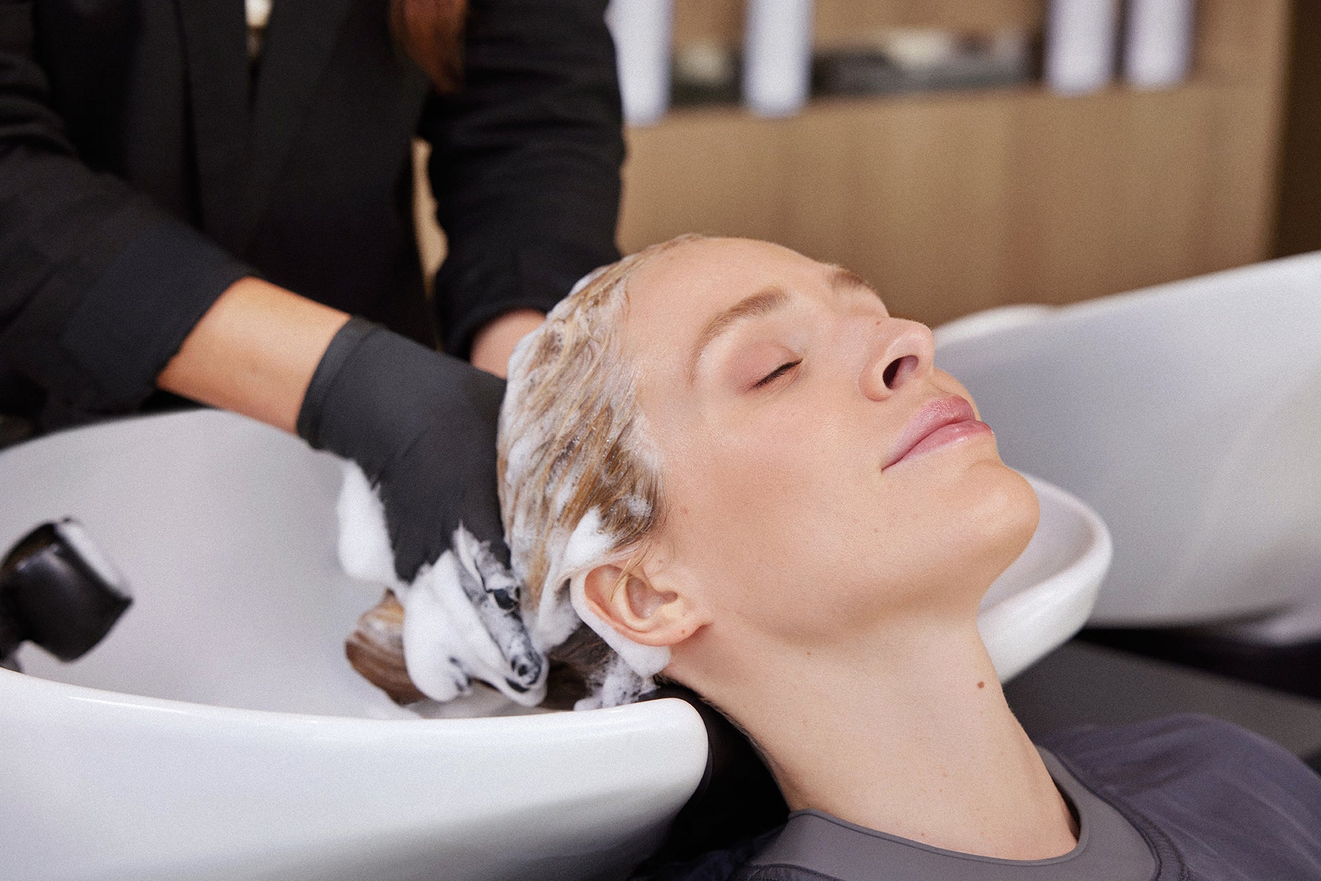 Person getting a hair wash at a salon with a stylist using gloves.