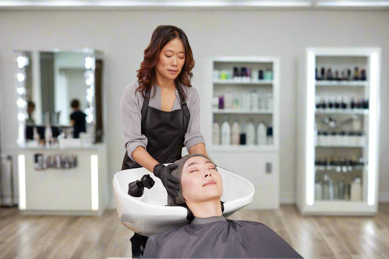 Woman getting a hair treatment at a salon with a customer in a chair.